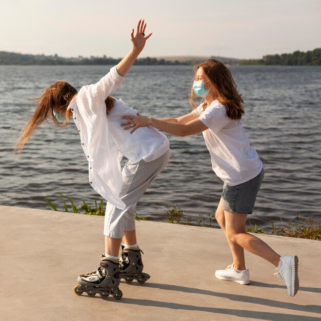 Vista lateral de dois amigos se divertindo com patins à beira do lago