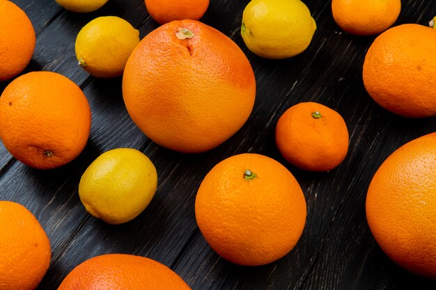 Vista lateral de frutas cítricas como limão tangerina laranja em fundo de madeira