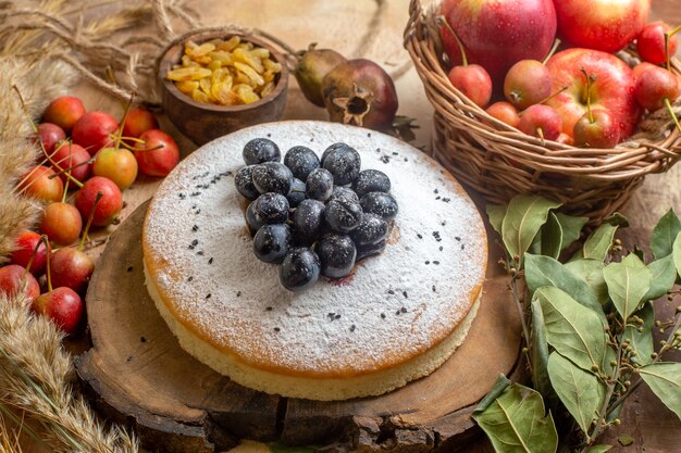 Vista lateral de frutas vermelhas - uma cesta de bolo apetitosa de frutas vermelhas, passas em tigelas, folhas de romãs