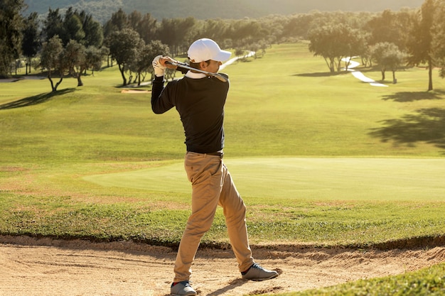 Vista lateral de homem jogando golfe com o taco