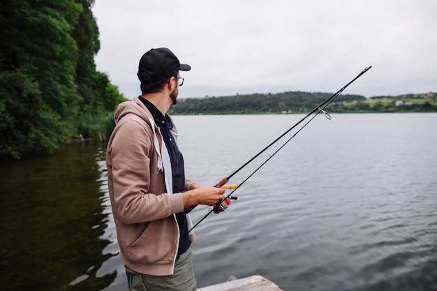 Vista lateral, de, homem jovem, segurando, cana de pesca