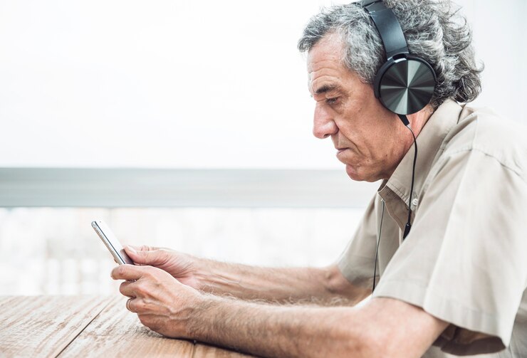 Foto grátis vista lateral, de, homem sênior, olhar, telefone móvel, escutar música, ligado, headphone