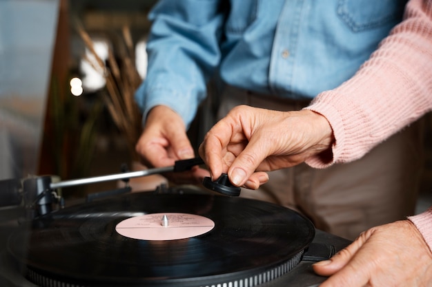 Vista lateral de idosos ouvindo disco de vinil