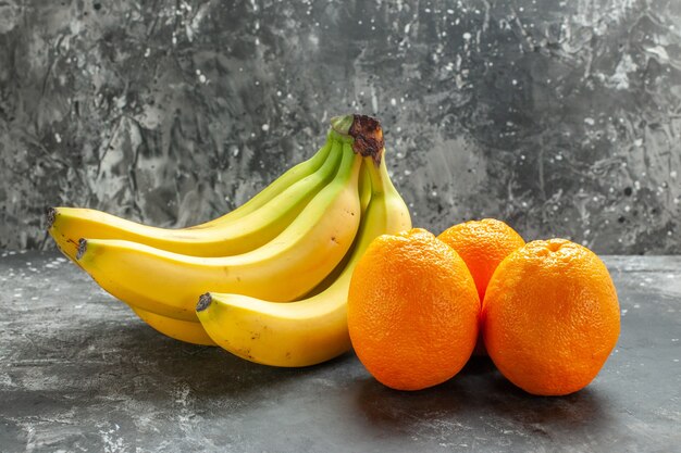 Vista lateral de laranjas frescas e bananas orgânicas naturais com fundo escuro