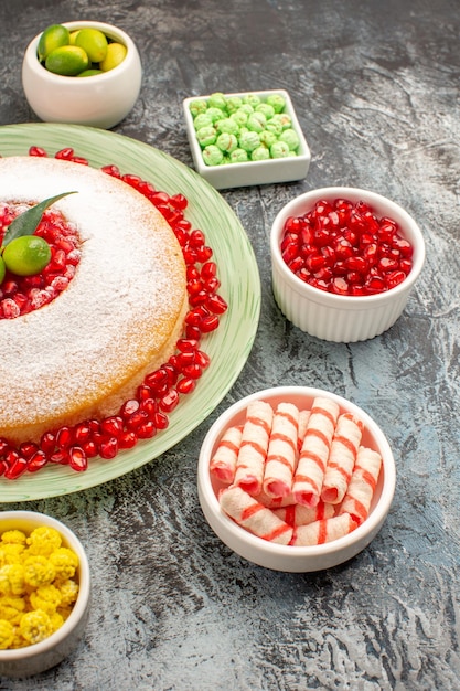 Vista lateral de longe bolo doces um bolo apetitoso com doces coloridos de romã e frutas cítricas