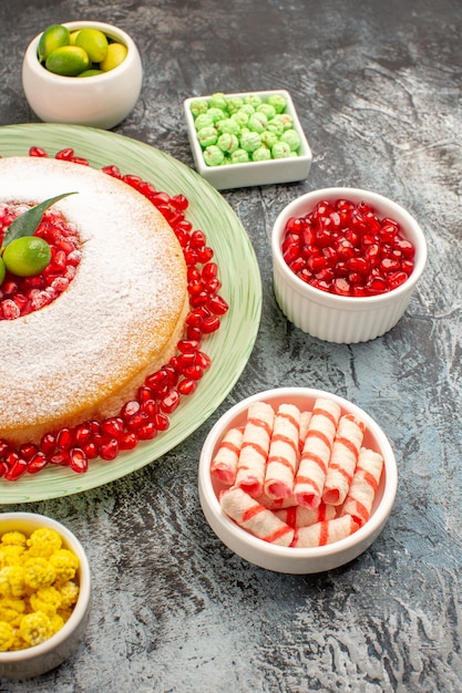 Foto grátis vista lateral de longe bolo doces um bolo apetitoso com doces coloridos de romã e frutas cítricas