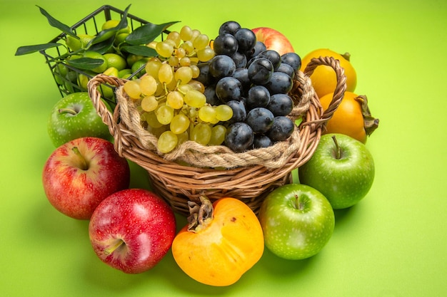 Vista lateral de longe frutas cesta de madeira de uvas maçãs caquis frutas cítricas