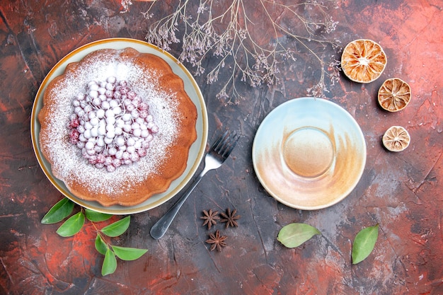 Vista lateral de longe um bolo um bolo com frutas silvestres folhas de limão garfo creme pires anis estrelado