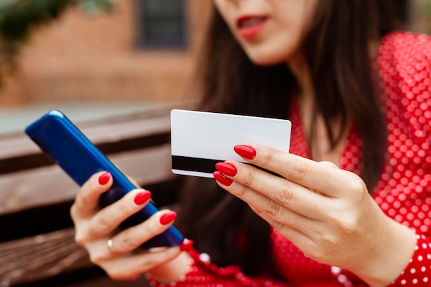 Vista lateral de mulher com smartphone e compra com cartão de crédito online