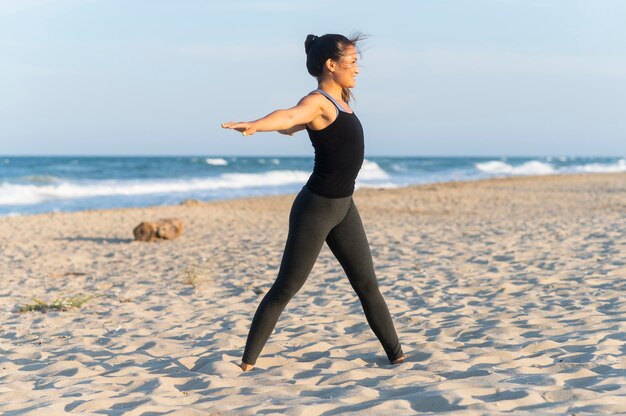 Vista lateral de mulher fazendo exercícios na praia