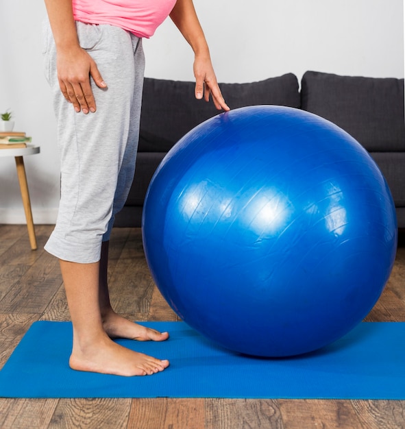 Vista lateral de mulher grávida em casa com bola e esteira para exercícios