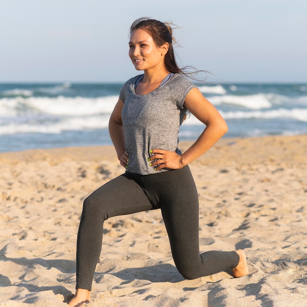 Vista lateral de mulher treinando na praia