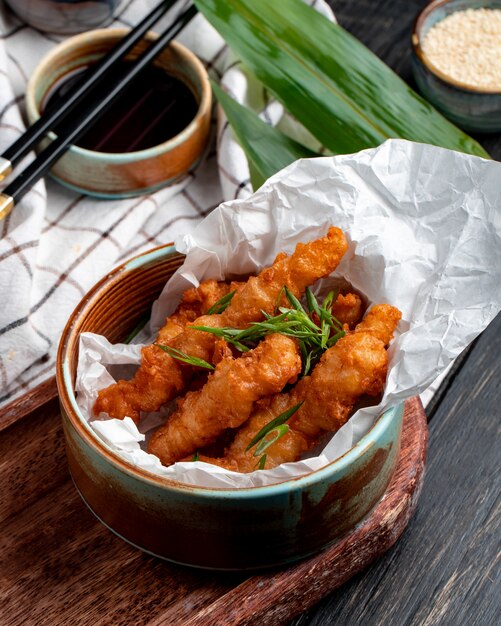 Vista lateral de nuggets de frango com ervas em uma tigela na toalha de mesa xadrez