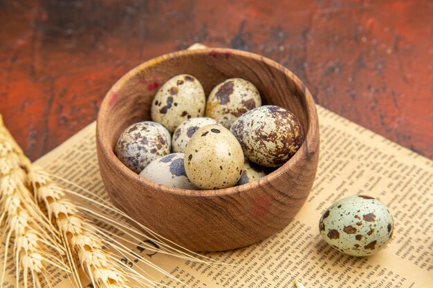Vista lateral de ovos frescos de fazenda dentro e fora de uma panela de madeira em um jornal velho em uma mesa marrom