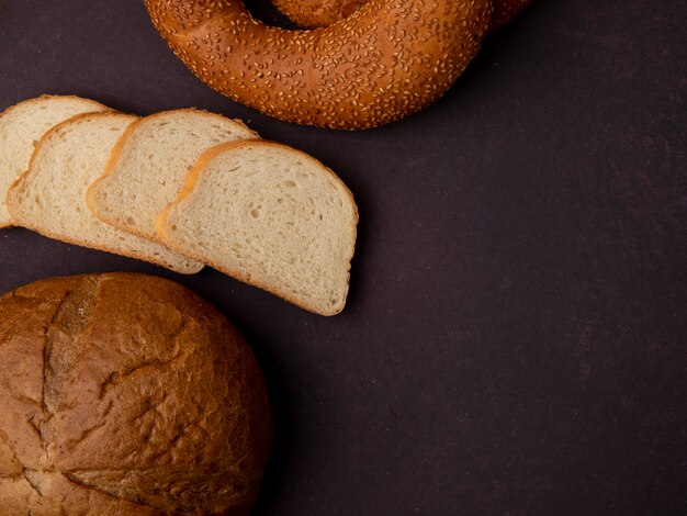 Vista lateral de pães como fatias de pão branco clássico cob e bagel em fundo marrom com espaço de cópia