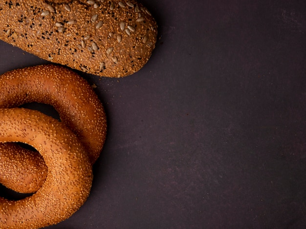 Vista lateral de pães como pão bagel e sanduíche no lado esquerdo e fundo marrom com espaço de cópia