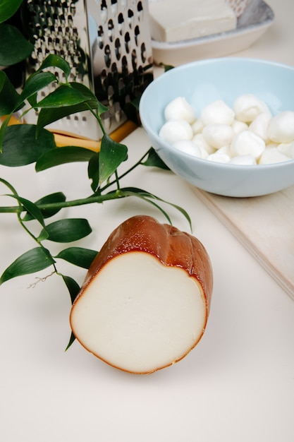 Vista lateral de queijo defumado em uma mesa com ralador e uma tigela cheia de mini queijo mussarela jpg