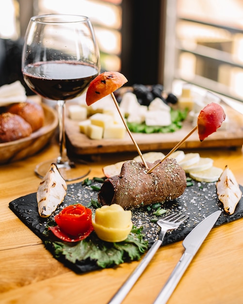 Vista lateral de rolo de carne com maçãs grelhadas e peras com um copo de vinho tinto