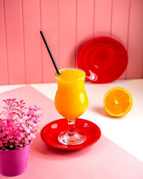 Vista lateral de suco de laranja fresco em vidro rosa
