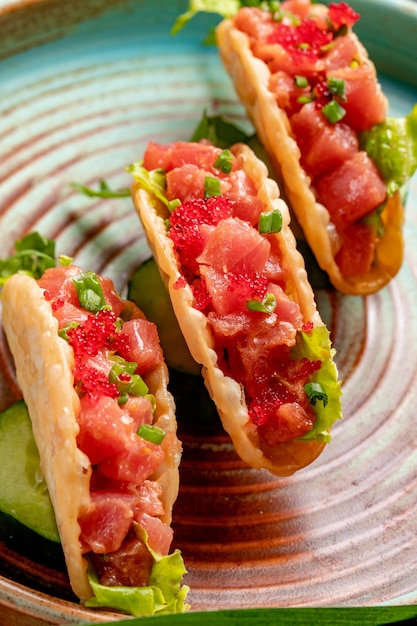 Vista lateral de tacos de salmão com caviar vermelho e cebola verde em um prato