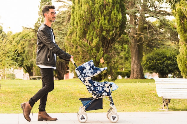 Foto grátis vista lateral, de, um, andar homem, com, carrinho bebê, parque