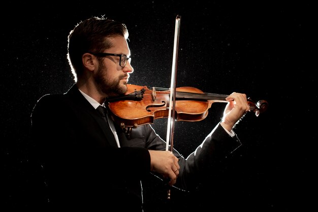 Vista lateral de um artista masculino tocando violino