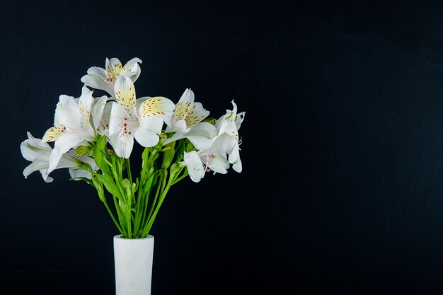 Vista lateral de um buquê de flores de alstroemeria cor branca em um vaso branco sobre fundo preto, com espaço de cópia