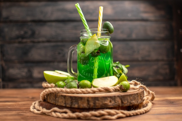 Vista lateral de um delicioso suco de fruta fresco servido com maçã e feijoas em uma tábua de madeira