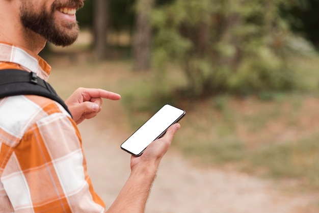 Vista lateral de um homem ao ar livre segurando um smartphone