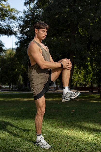 Vista lateral de um homem com pulseira de ginástica, malhando ao ar livre