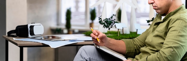 Vista lateral de um homem com uma prancheta pesquisando um projeto de energia eólica ecologicamente correto