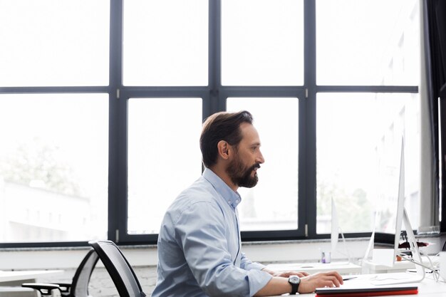 Vista lateral de um homem de negócios, trabalhando em um computador