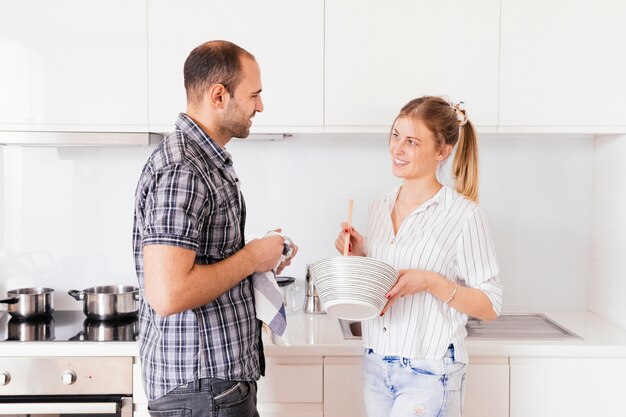 Vista lateral, de, um, homem jovem, ajudando, seu, esposa, preparando alimento, cozinha