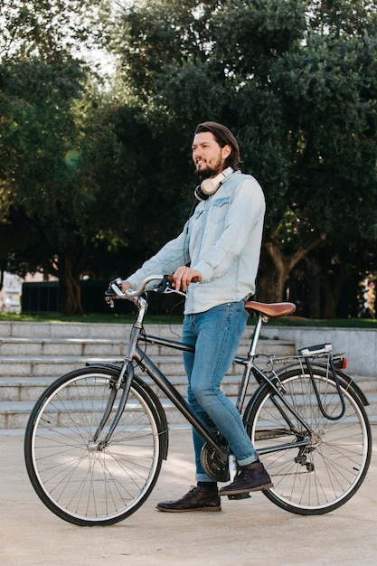 Vista lateral, de, um, homem jovem, ficar, com, bicicleta, parque