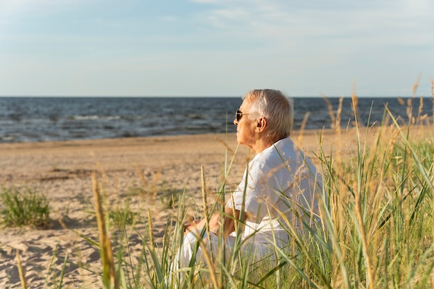 Vista lateral de um homem mais velho aproveitando o tempo na praia