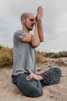 Foto grátis vista lateral de um homem meditando do lado de fora enquanto pratica ioga
