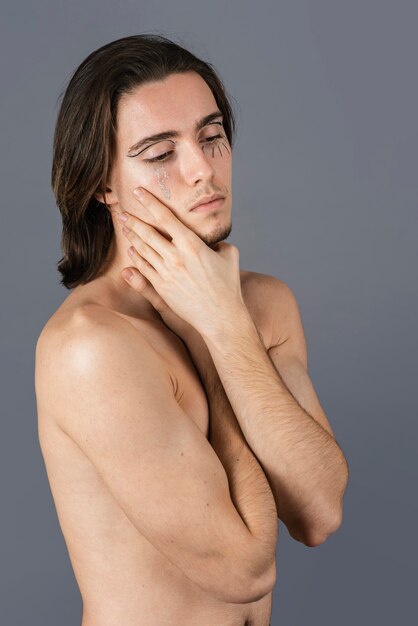 Vista lateral de um homem sem camisa com maquiagem