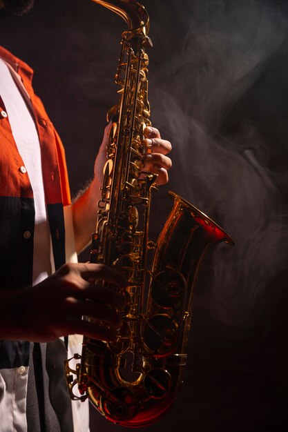 Vista lateral de um homem tocando saxofone em destaque