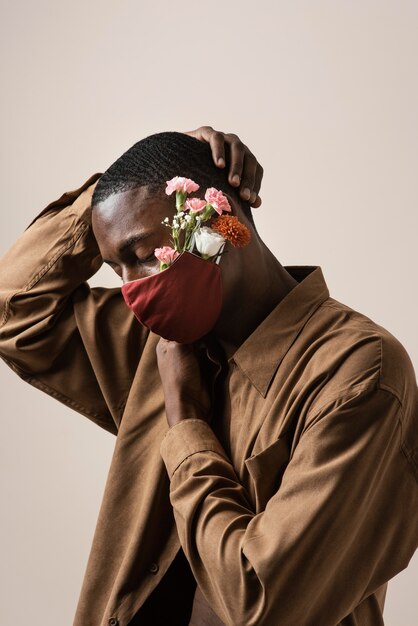 Vista lateral de um homem usando máscara facial e flores