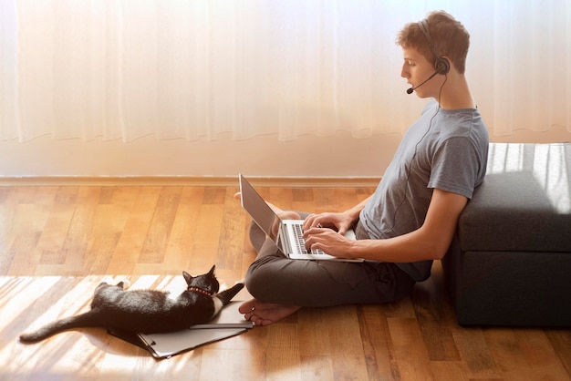 Foto grátis vista lateral de um homem usando o laptop em casa em quarentena para trabalhar