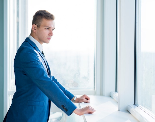 Vista lateral, de, um, jovem, homem negócios fica, perto, janela, em, escritório