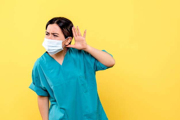 Vista lateral de um médico de máscara ouve queixas de pacientes com cobiça