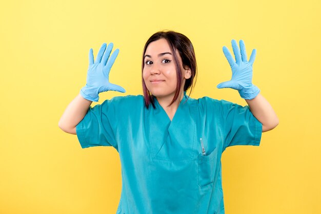 Vista lateral de um médico sorrindo, médico com luvas médicas na parede amarela