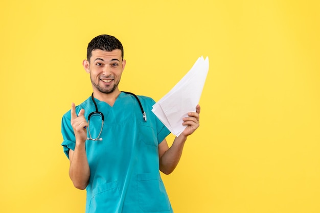 Vista lateral de um médico sorrindo, médico de uniforme médico na parede amarela