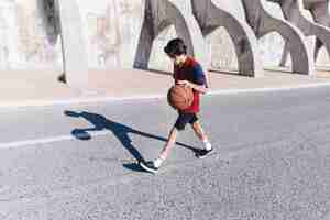 Foto grátis vista lateral, de, um, menino adolescente, jogando basquetebol, perto, cercar, parede