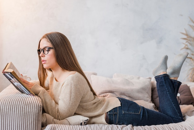 Vista lateral, de, um, mulher jovem, mentindo livro leitura cama