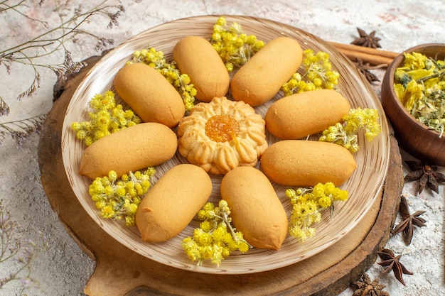 Foto grátis vista lateral de um prato de biscoitos e algum tipo de ervas secas ao redor sobre o mármore