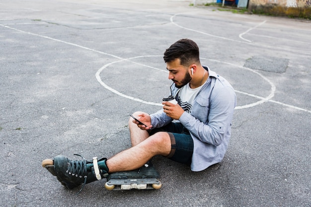 Foto grátis vista lateral, de, um, relaxado, macho, rollerskater, usando, telefone móvel