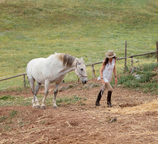 Vista lateral de uma agricultora com seu cavalo ao ar livre