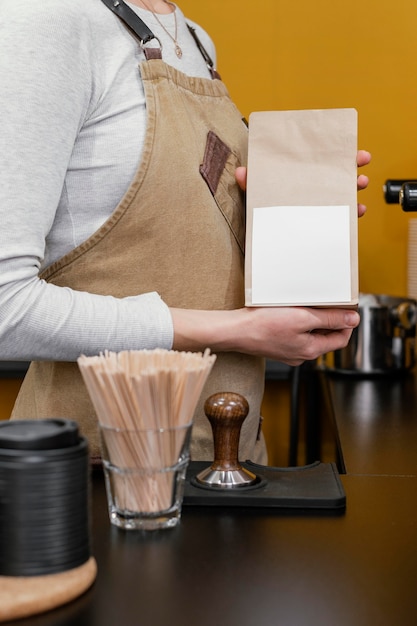 Vista lateral de uma barista segurando uma sacola de café de papel